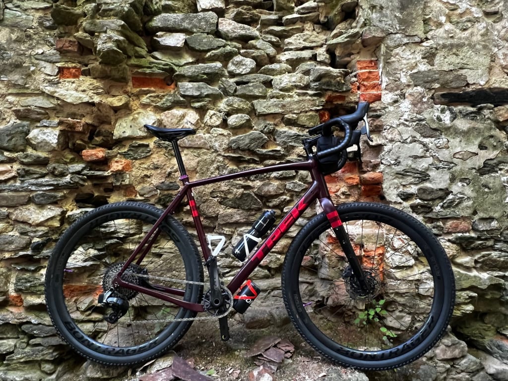 Red and black road bike on Bontrager tires against a stone wall